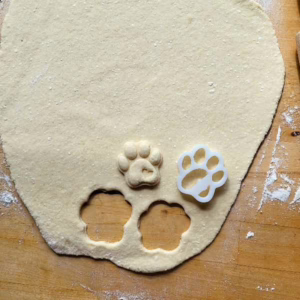 Ein ausgerollter Teig mit zwei ausgestochenen Keksen und der Ausstechform